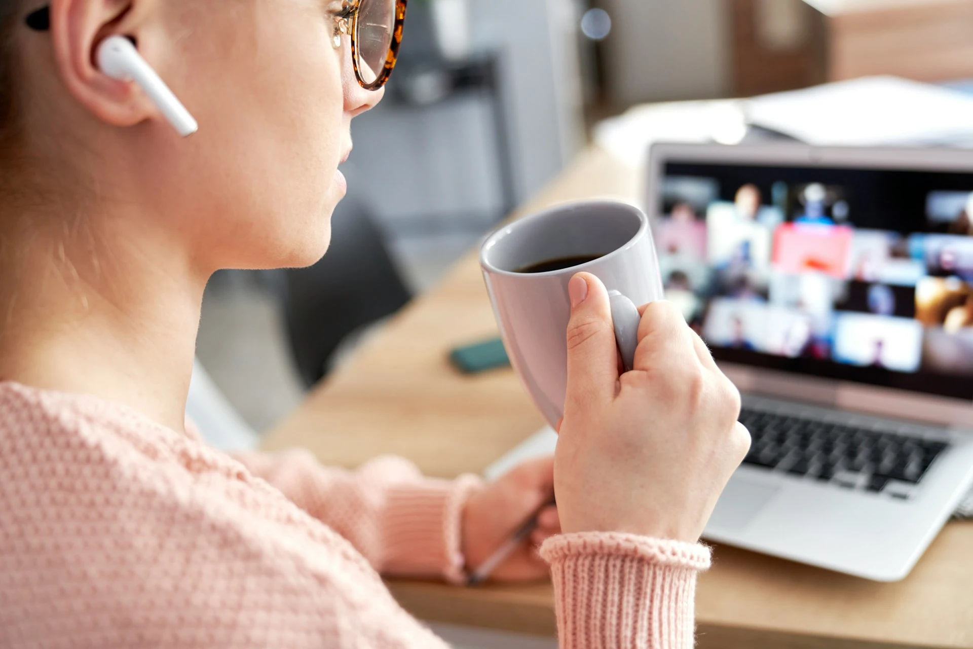 A woman attending an online meeting with multiple participants on her laptop.