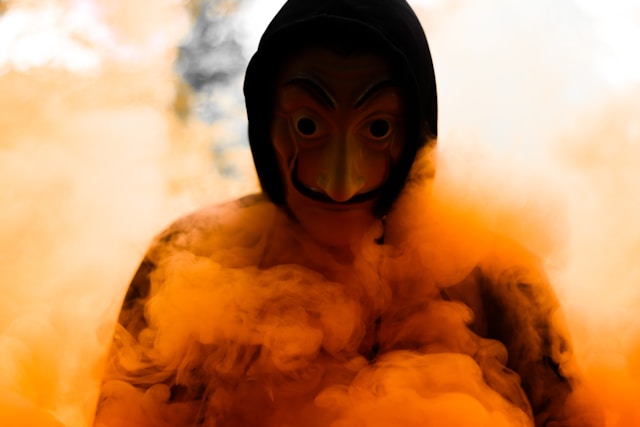A person wearing a Casa de Papel mask in a smoky environment.