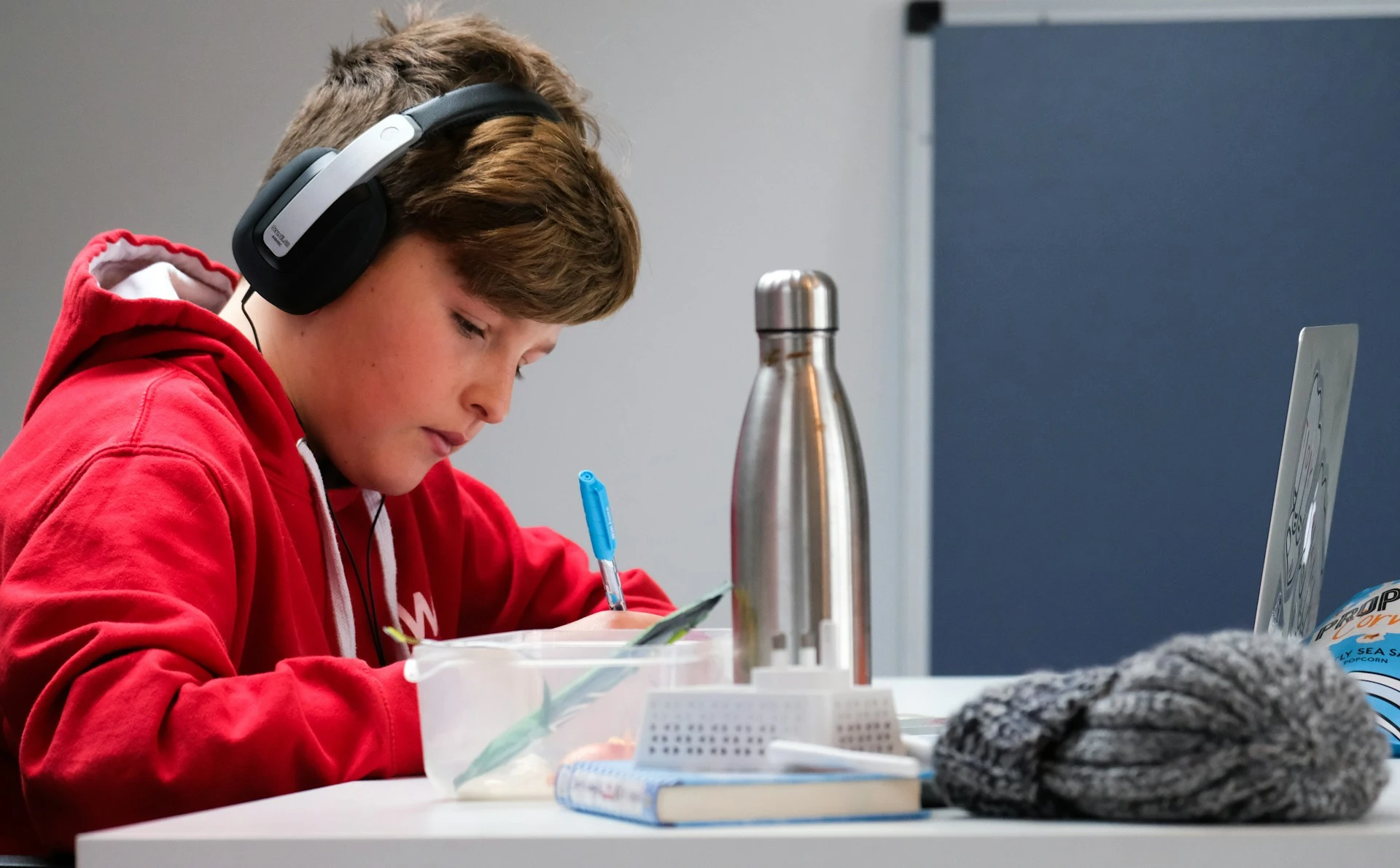 A young boy sits at a desk, focused on writing.