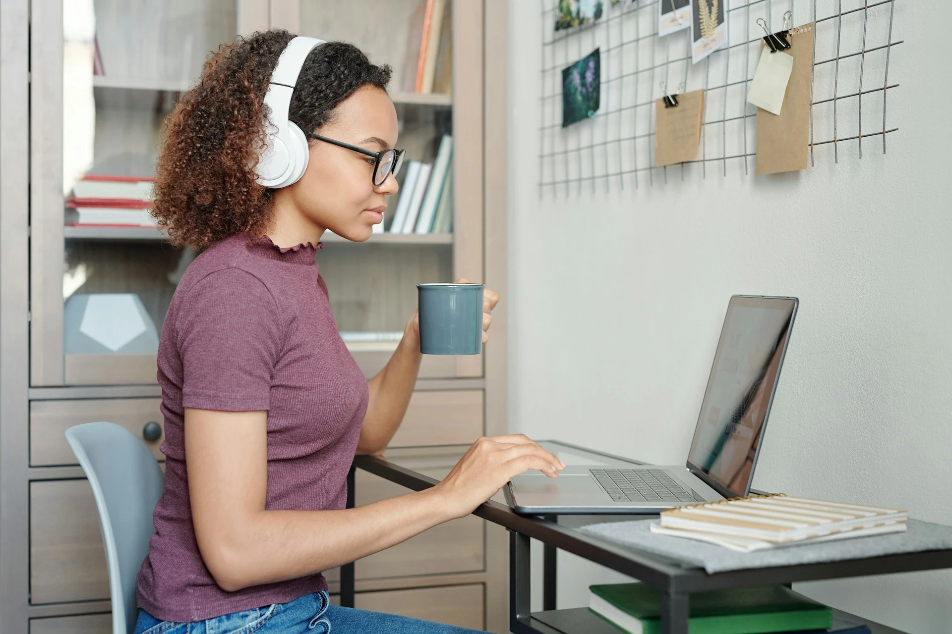 A student wearing headphones, focusing on an educational video on her laptop.