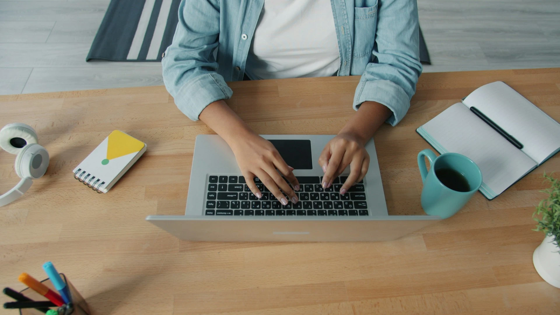Top-down view of a person typing on a laptop at a wooden desk.