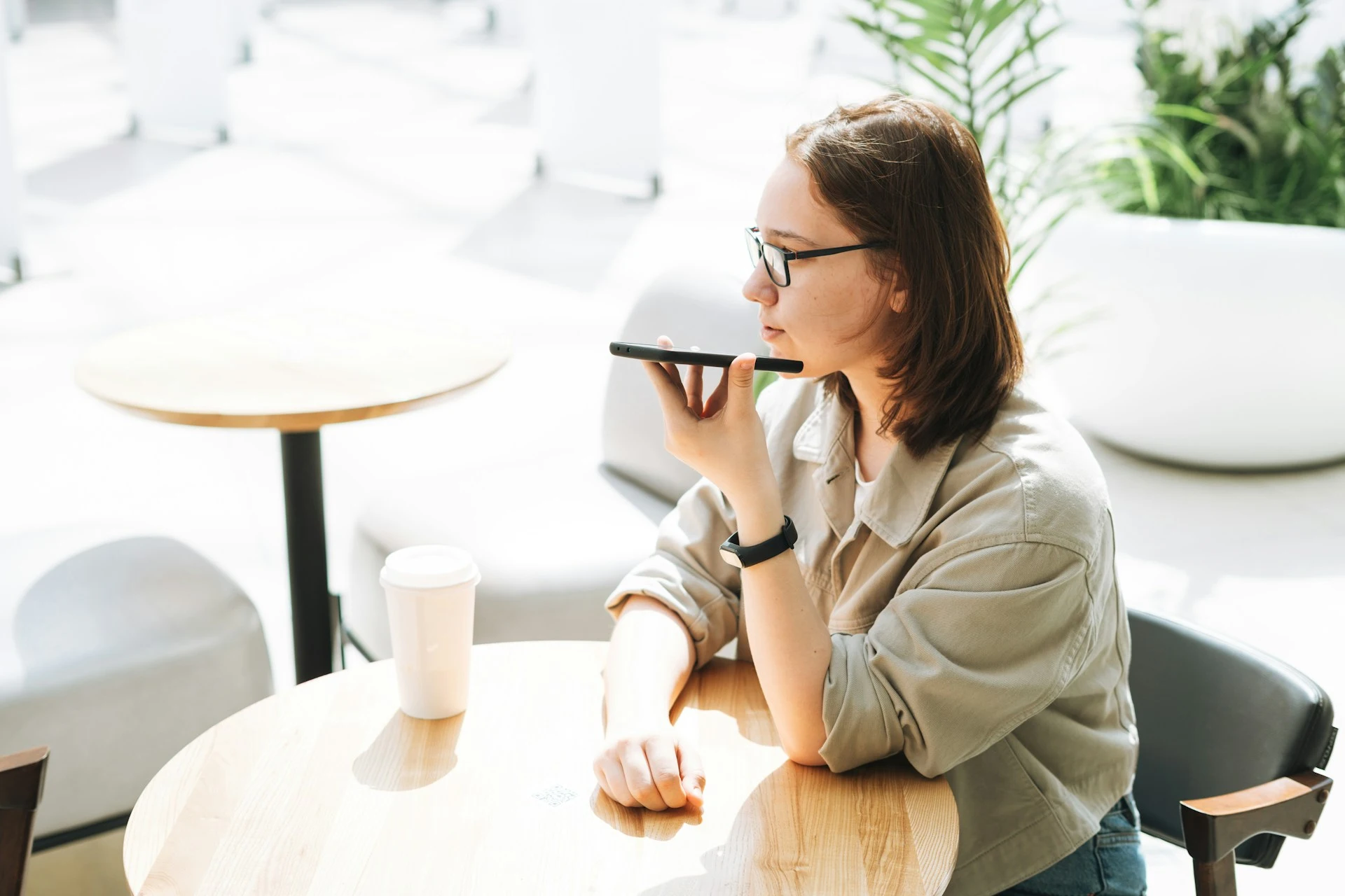 Woman speaking into her phone at a cafe.