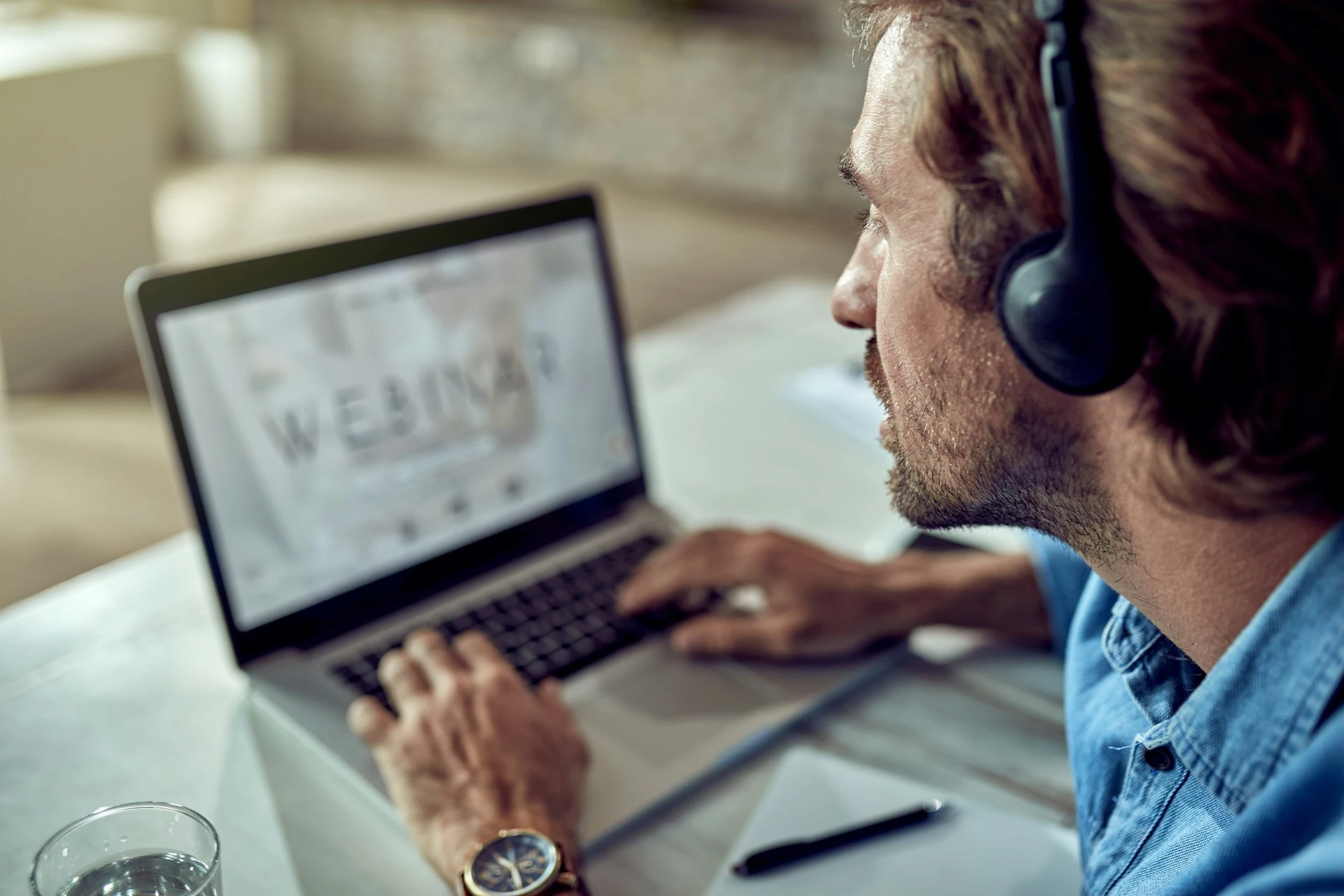 A man looking at a laptop screen that displays the word "WEBINAR."