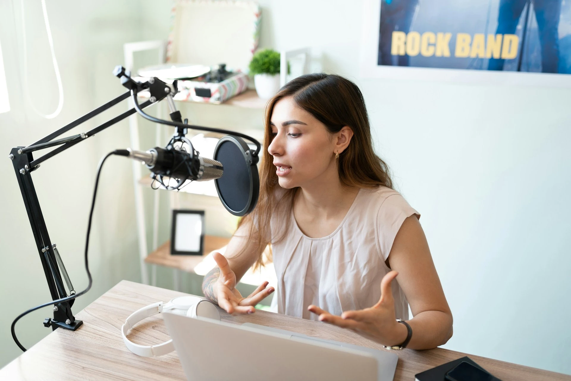 A woman speaking into a professional microphone and pop filter in a home studio.