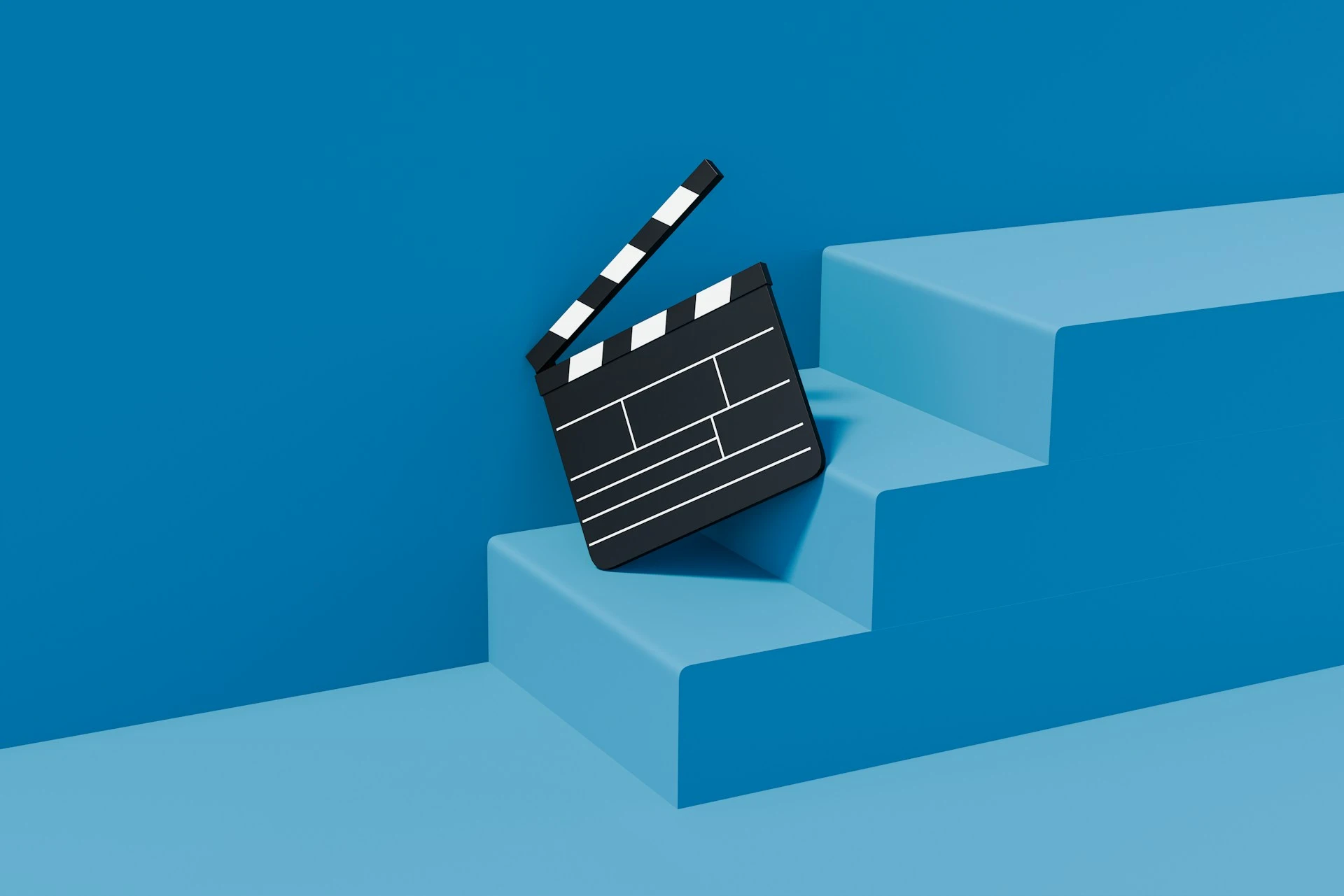 A 3D black clapperboard leaning on blue stairs.