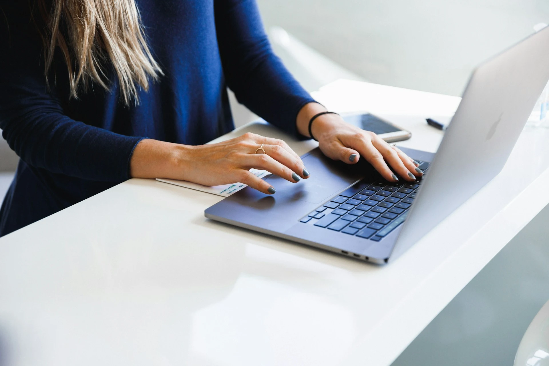  A person's hands typing on a laptop keyboard.
