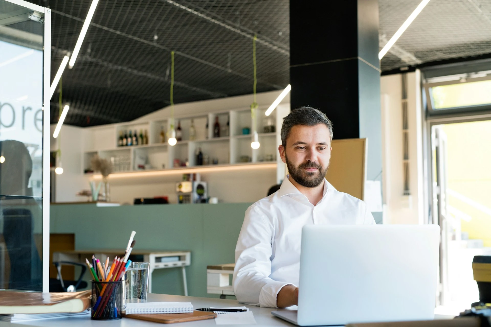 A man works on a laptop in a bright, modern office.