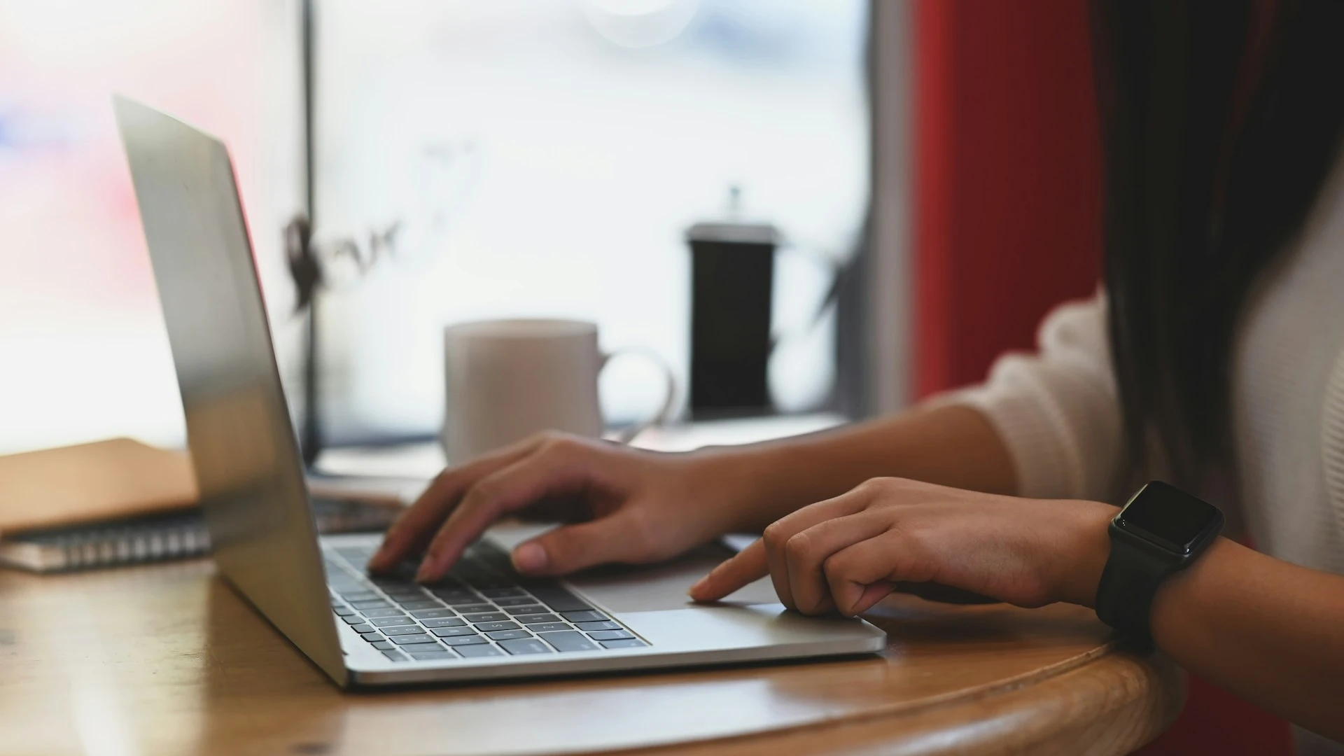  A close-up of a person's hands typing on a laptop keyboard. 