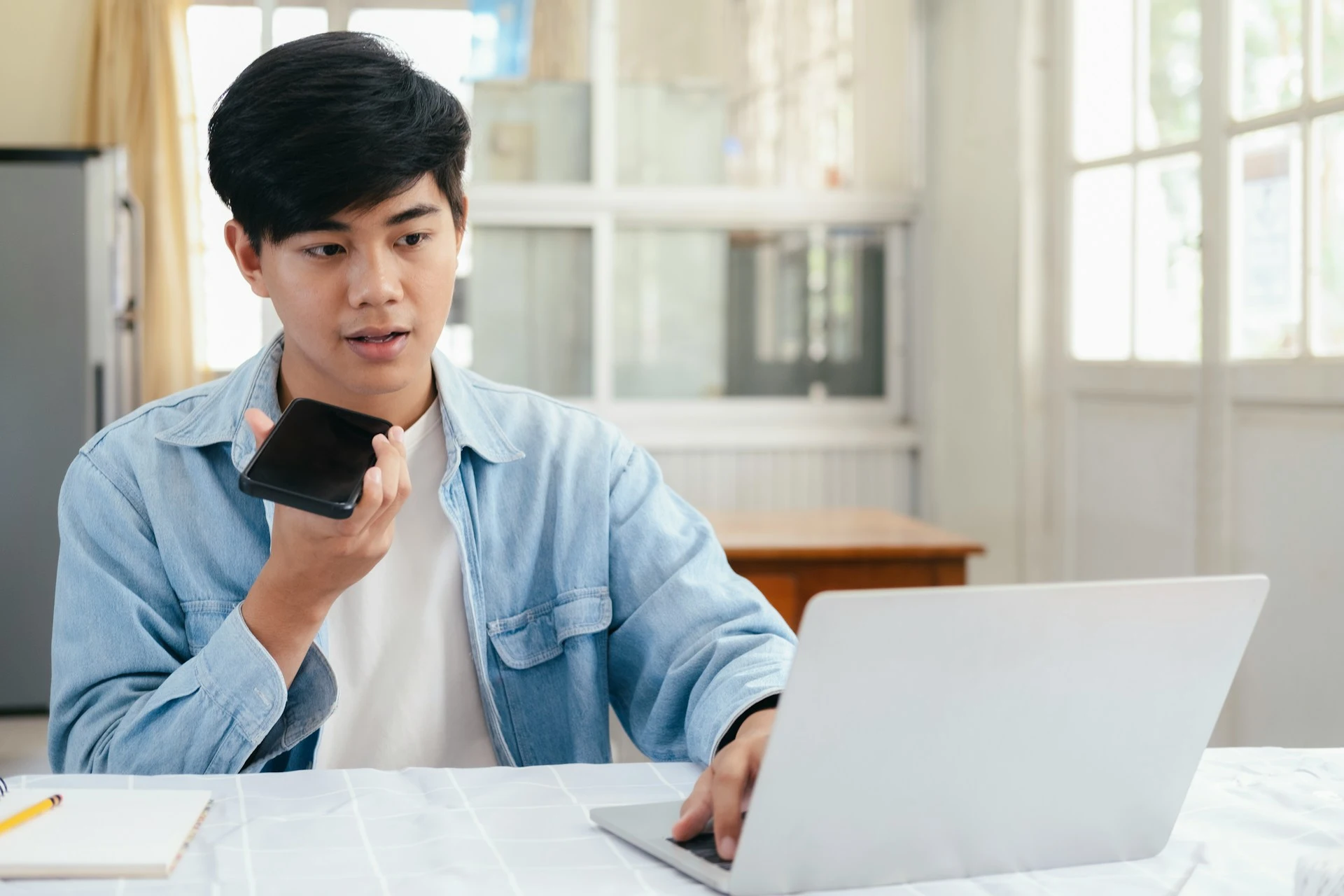  A man holding his phone up to his mouth, speaking into it to use a voice-to-text feature.