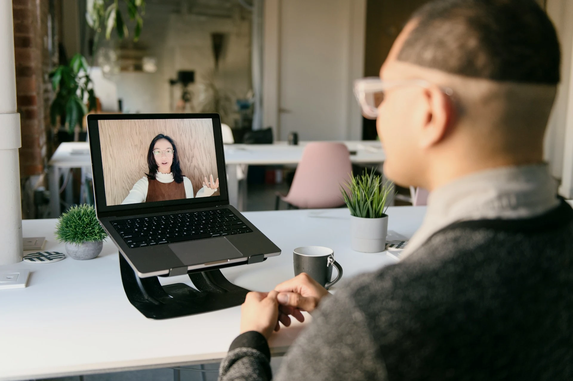 Person attending a video meeting on a laptop in a modern office.
