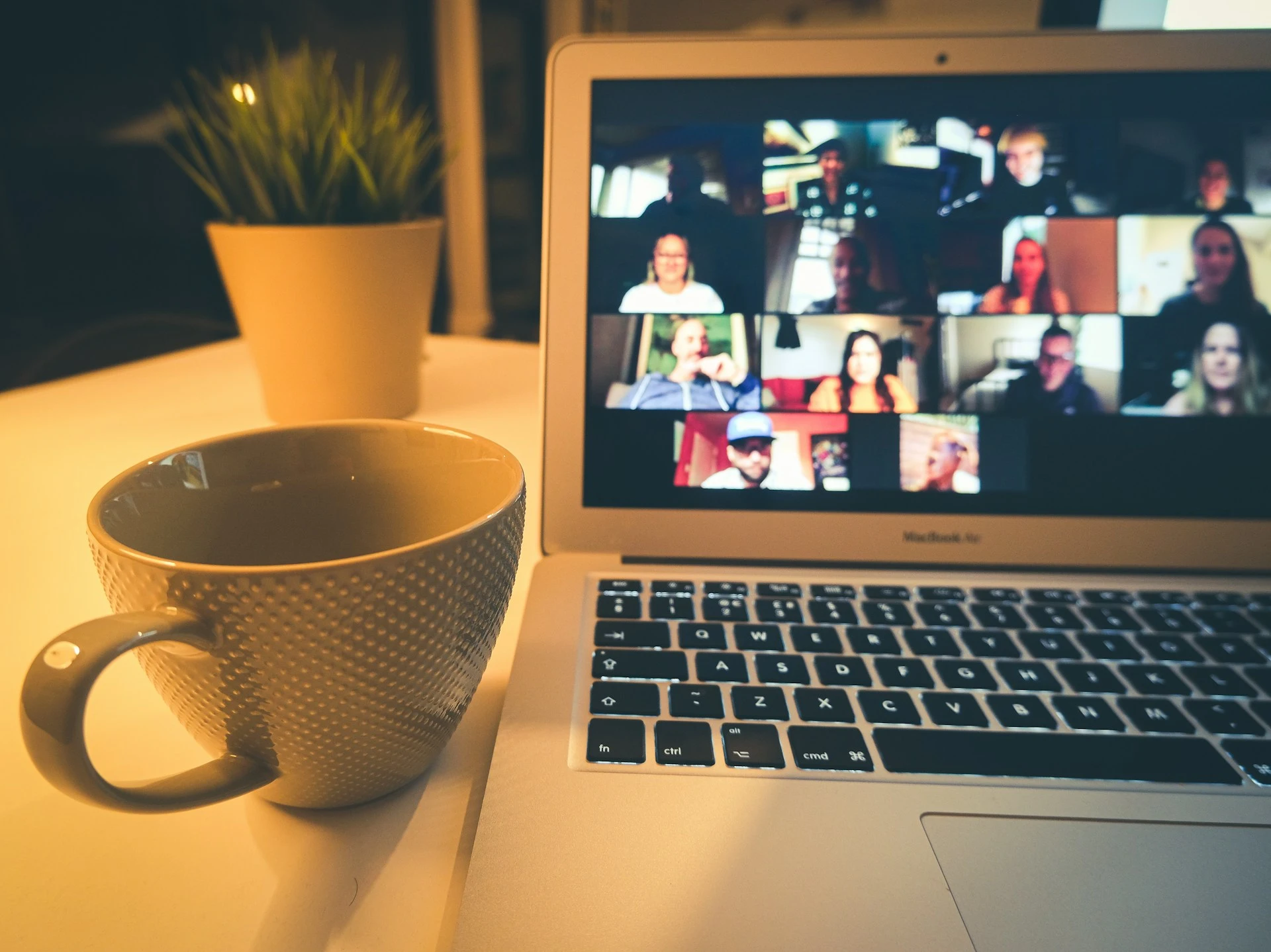 A laptop on a desk showing a video conference call with multiple participants.