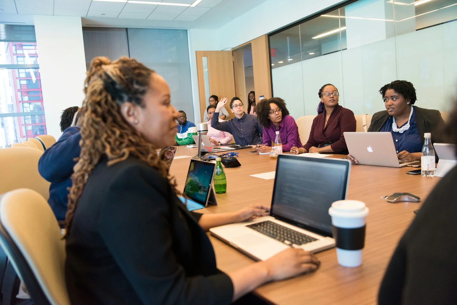 A group of colleagues sitting around a conference table with laptops during a meeting or training session.