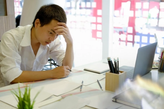 An exhausted student studying at a desk.