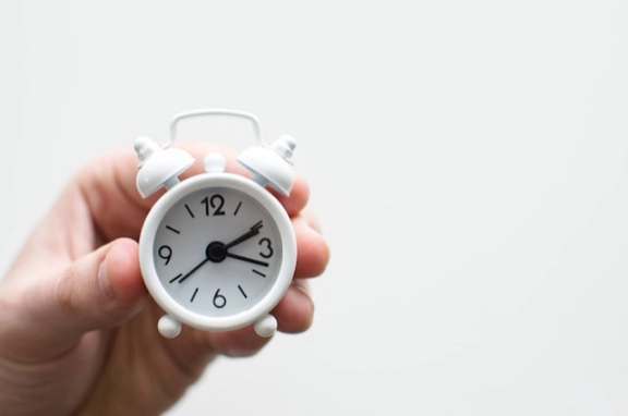 A hand holding a mini alarmclock.