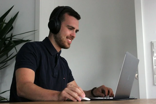 Man transcribing interviews on his laptop with his phone.