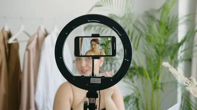 A woman holding a lipstick, shooting a talking head video.