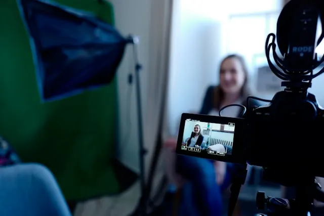 A woman sitting on a chair and talking on camera.