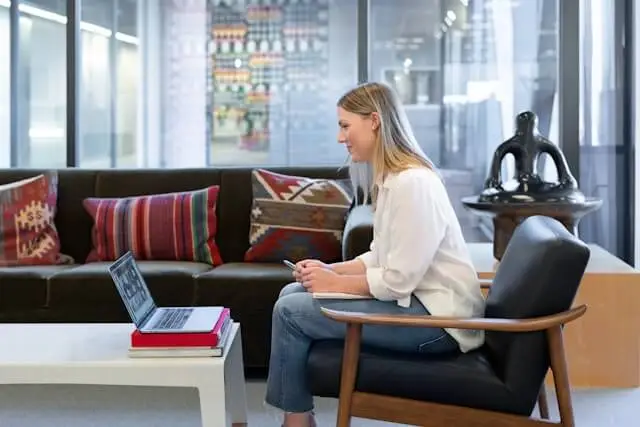 A woman sitting on a chair and conducting a virtual meeting via her laptop.