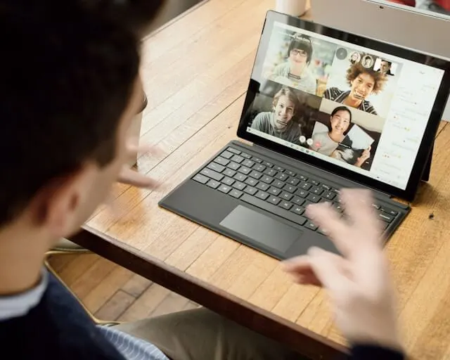 A man having a virtual meeting with four other people via his laptop.