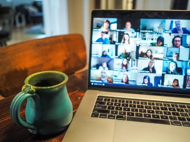 A laptop screen displaying a virtual meeting with a group of people.