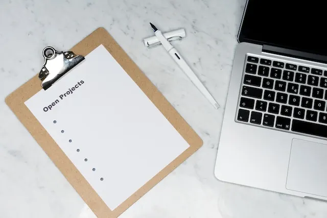 A bullet list titled "Open Projects" on a white marble table and near a laptop.