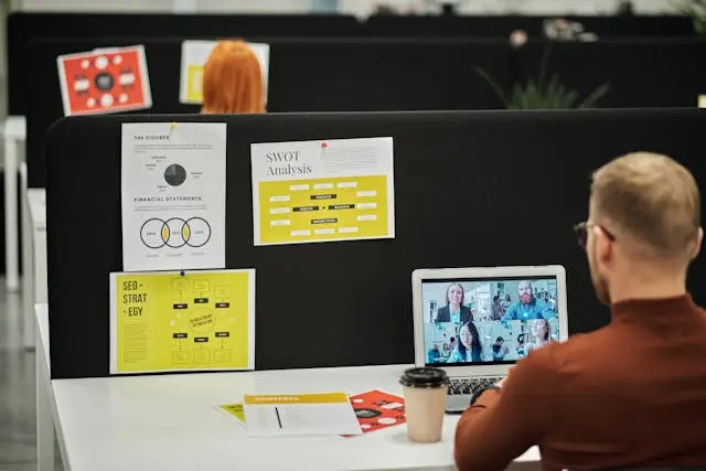 A man with glasses having a virtual meeting at his office.