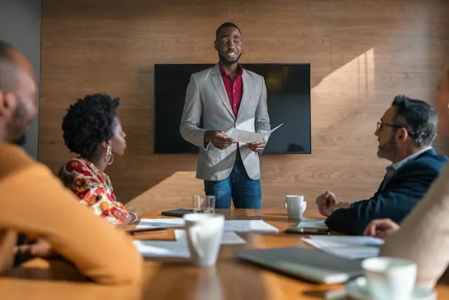 A young manager going over paperwork in a meeting with his team.