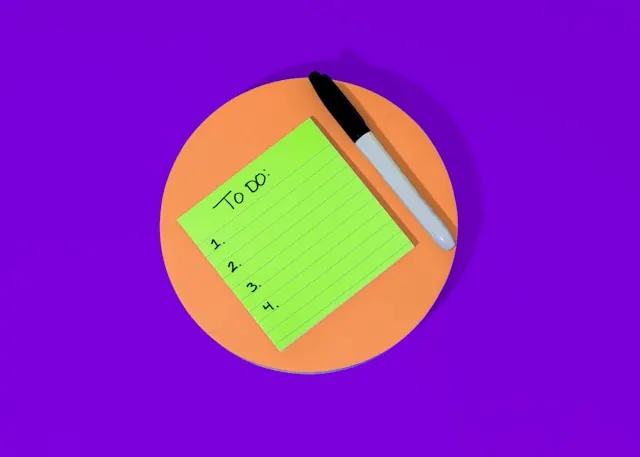 An empty to-do list on a green post-it with a black pen marker it.