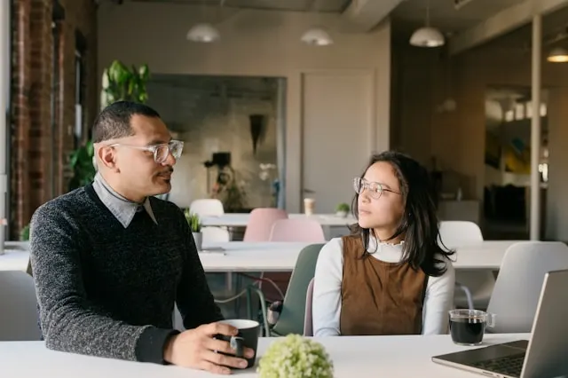 A man and a woman sitting at a table and having a one-on-one meeting.