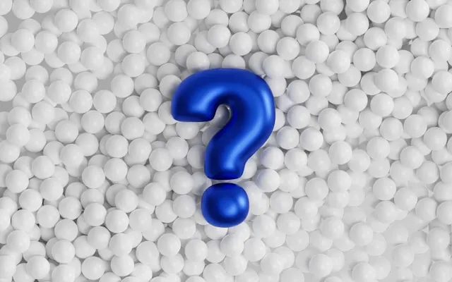 A blue question mark on a surface of white balls.