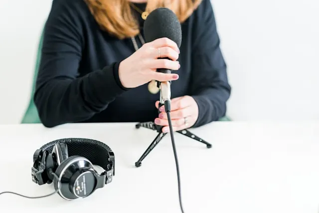 A woman sitting at a table and grabbing a microphone.