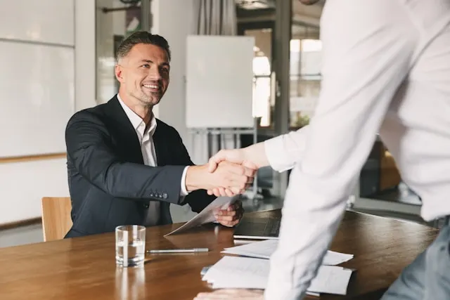 Two men shaking hands while one of them is leaving.