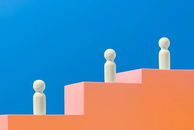 White figures on an orange staircase, representing best exit interview questions on career advancement.