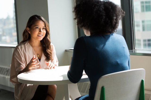 Two women sitting at a table and talking.