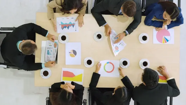 A group of business people showing each other data charts around a table.