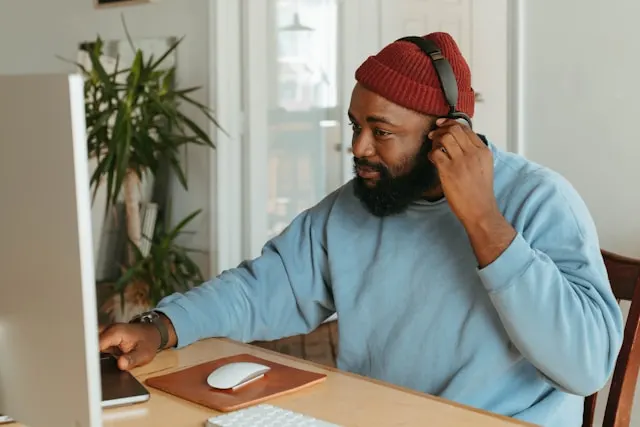 A man working on his computer while wearing headphones.