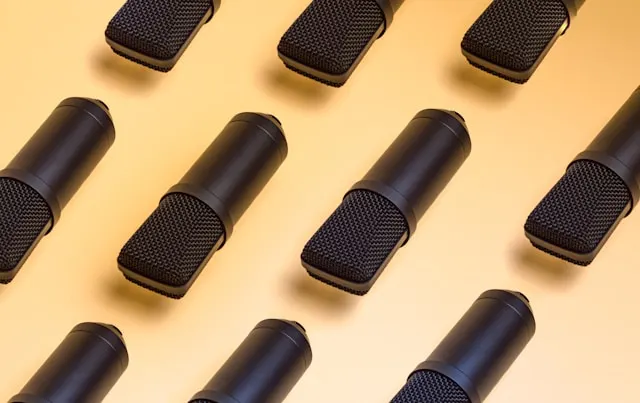 A group of black microphones on orange surface.