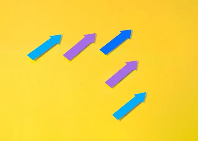 Blue and purple arrows on yellow surface, representing performance review questions on professional growth.