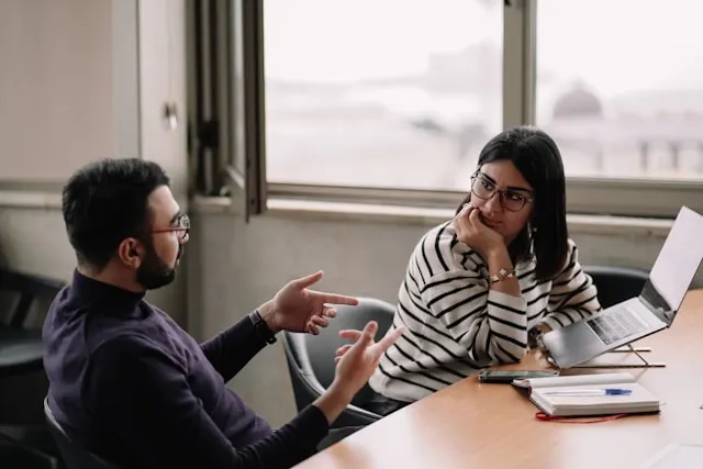 A man and a woman sitting at a table and talking.