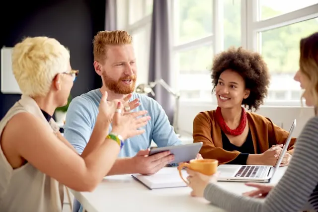 Four people sitting around a table and talking in an office.