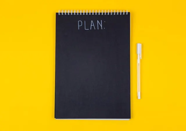 A black notebook with the word "Plan" written on it.