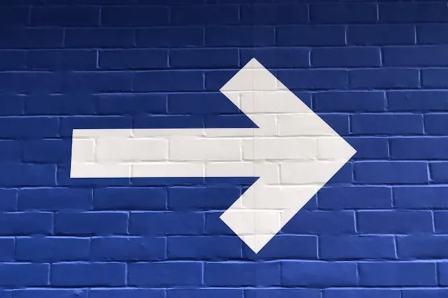 A white arrow painted on a blue wall.