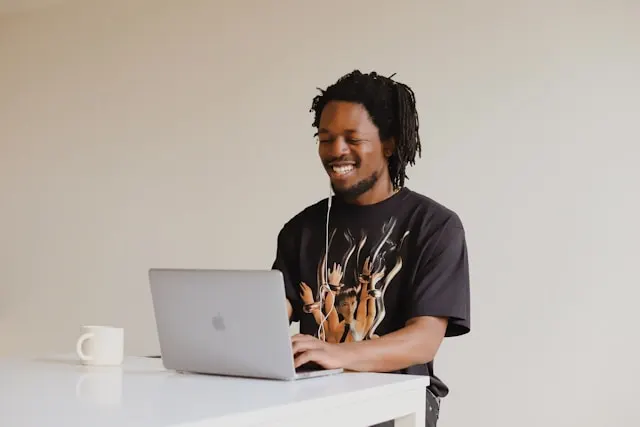 A man smiling while working on his laptop.