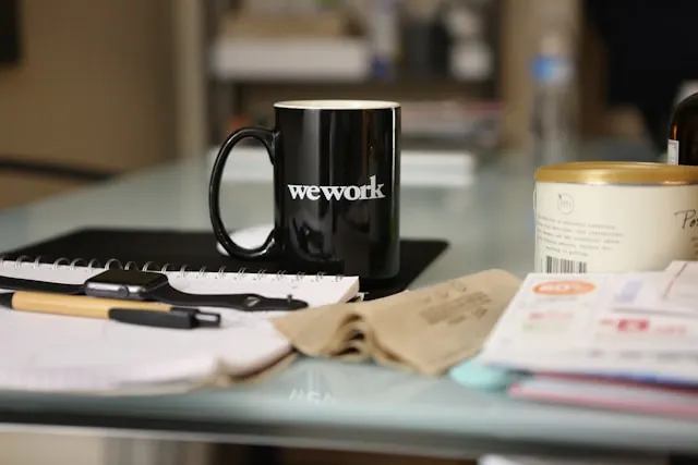 A black WeWork mug on a desk.