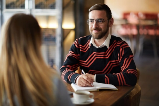 A man listening to the other person attentively while taking notes.