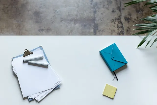 A white table topped with papers, markers, and a post-it.