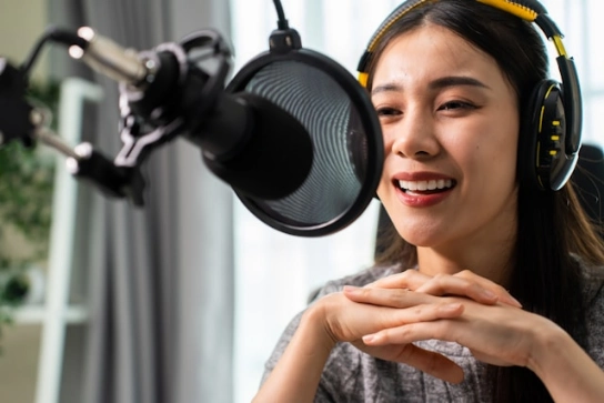 A woman wearing headphones and speaking to a microphone.