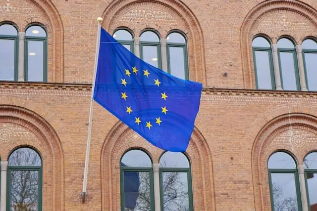 The European Union flag in front of a brick building.