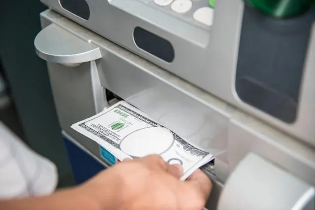 Close-up shot of a hand getting money from an ATM.