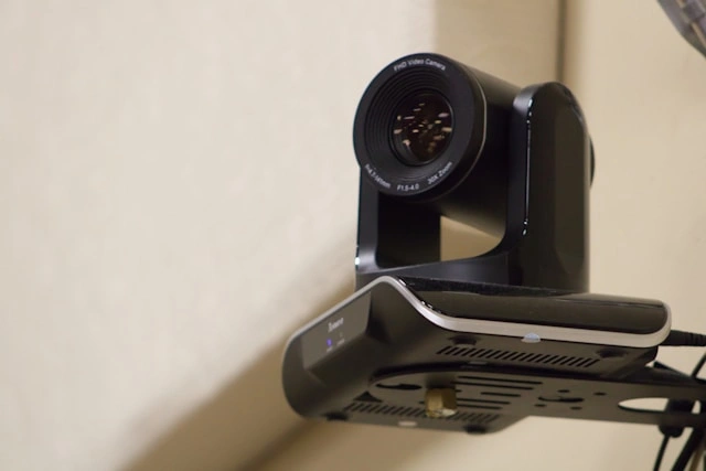 A wall-mounted PTZ camera, an important element of hybrid meeting equipment.